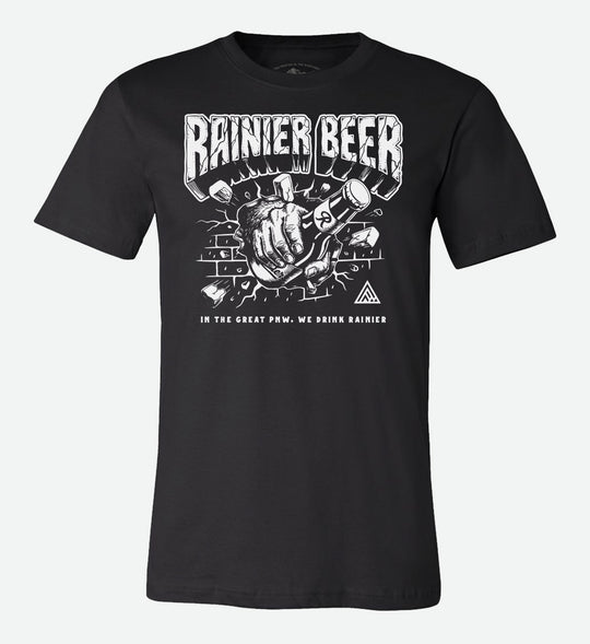 Black t-shirt by The Great PNW featuring a graphic illustration of a hairy Sasquatch hand holding a bottle of Rainier Beer and smashing through a brick wall. Bold text reads "RAINIER BEER" at the top and "IN THE GREAT PNW, WE DRINK RAINIER" at the bottom.